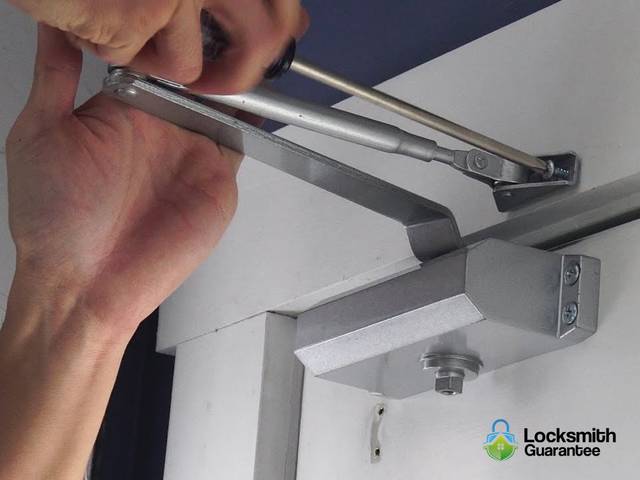 Door closer arm being adjusted above a doorway